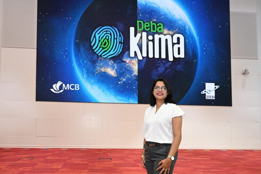A woman poses in front of a sign reading "Deb Klima."