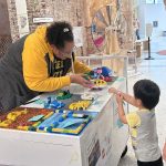 Young child explores LEGO creation with builder Marcella Spear