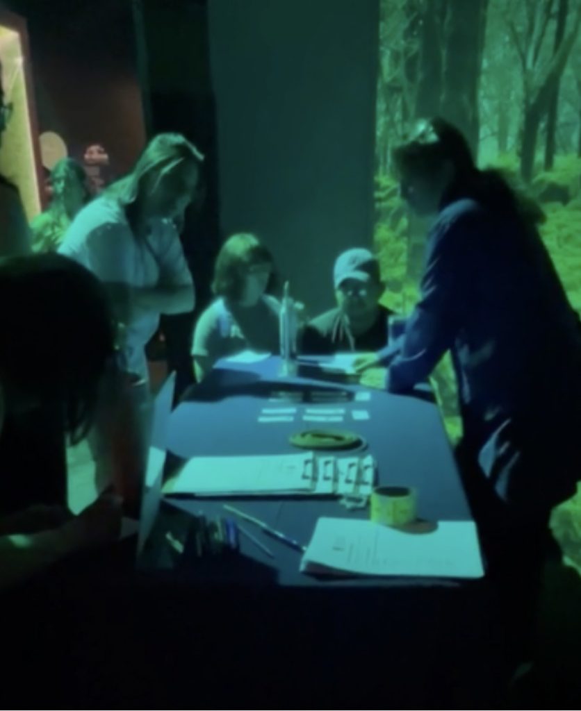 An educator and 3 museum guests engage in a hands-on activity