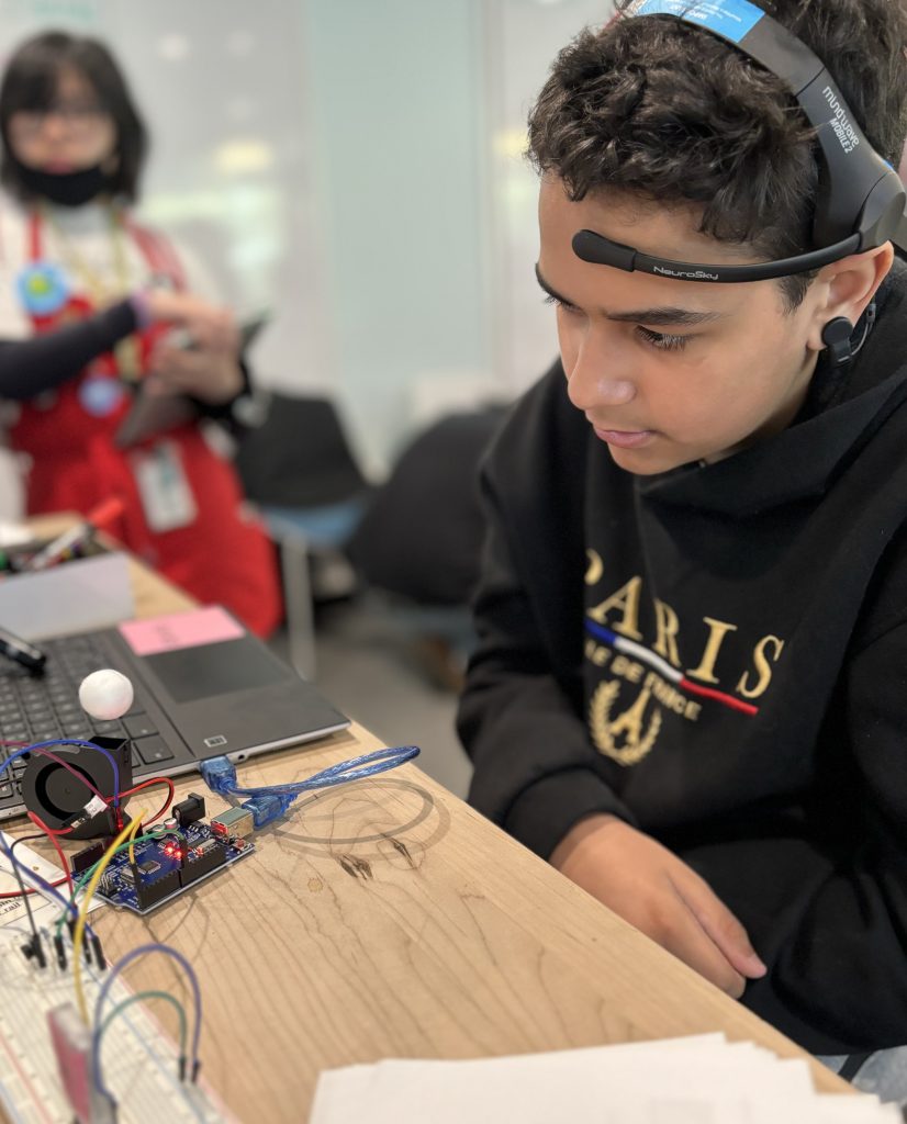 A tween boy works on coding his BCI project