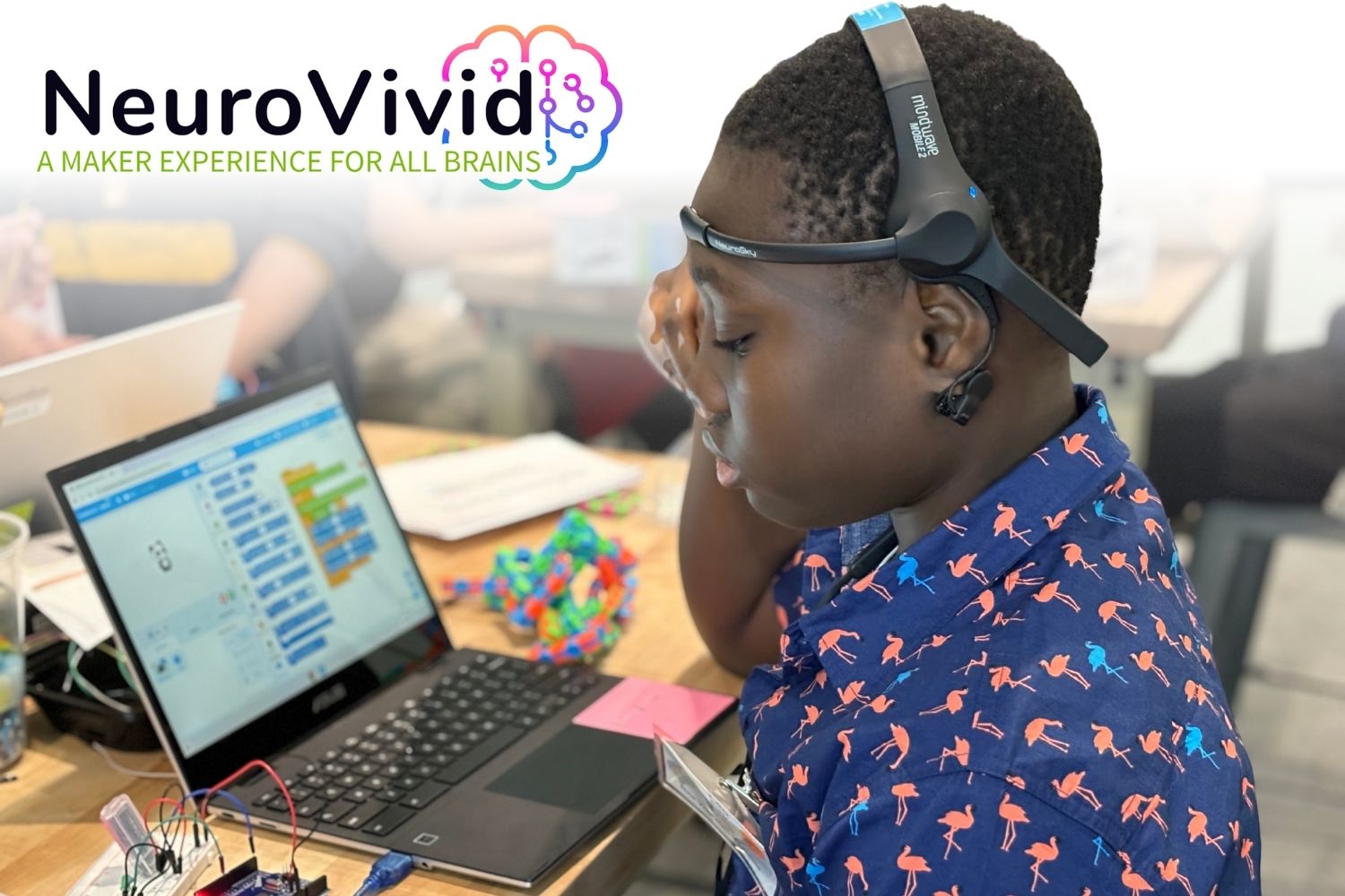 NeuroVivid logo overlaid on a photo. A tween boy sits at a desk, looking intently at a laptop screen, which displays a coding interface. Next to the laptop is a circuit board. On his head, he wears a headset.